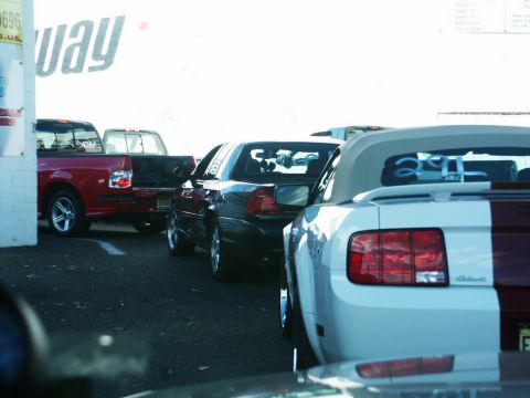 2001 Mercury Grand Marquis - A black sedan is seen parked behind two pickup trucks in a lot.