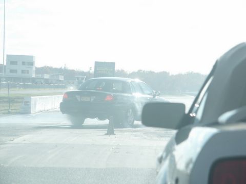 2001 Mercury Grand Marquis - A black 2001 Mercury Grand Marquis sedan is seen from behind, with smoke billowing from its tires on a track.
