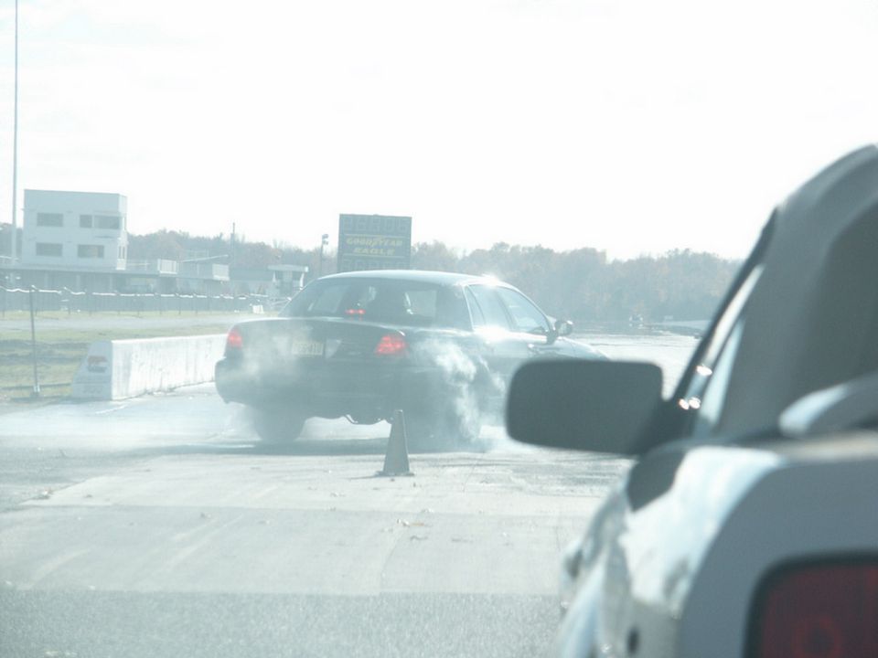 Rear view of a black 2001 Mercury Grand Marquis doing a burnout at a drag strip