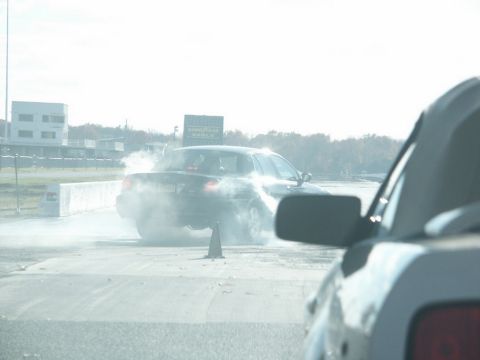 2001 Mercury Grand Marquis - Car performs a burnout on a drag strip, kicking up smoke. Another vehicle is in the foreground.
