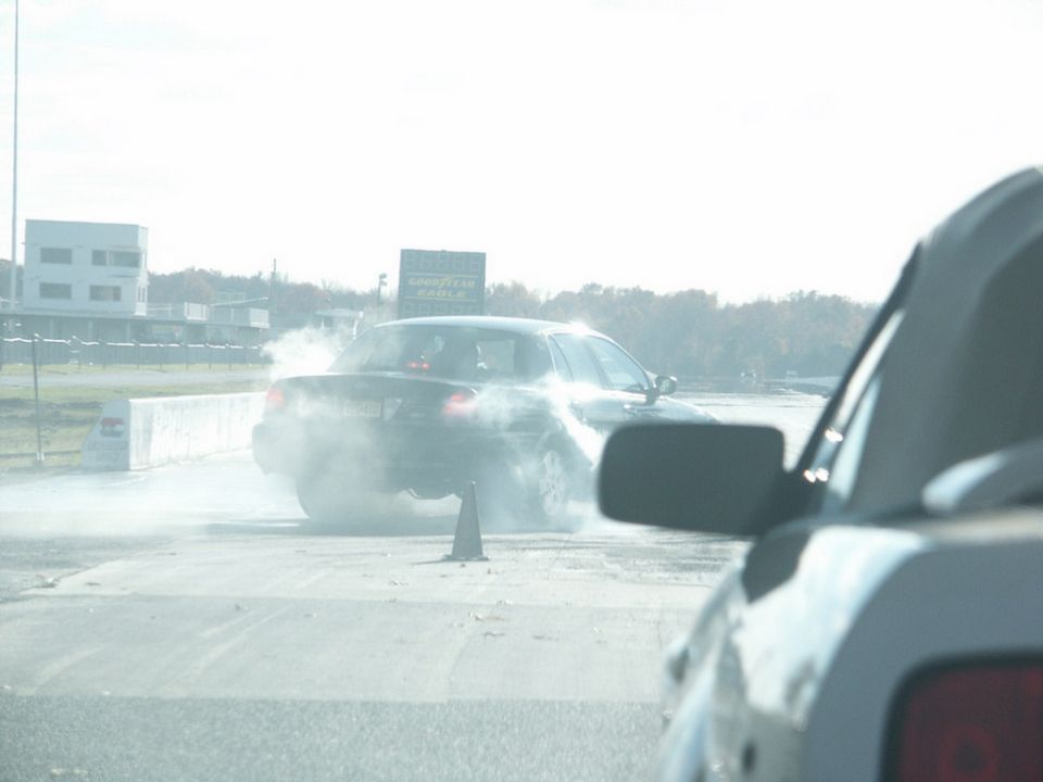 2001 Mercury Grand Marquis doing a burnout on a drag strip, viewed from another car