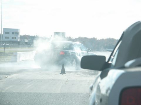 2001 Mercury Grand Marquis - A car is engulfed in smoke during a burnout on a race track, with another vehicle visible in the foreground.