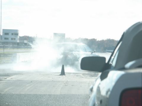 2001 Mercury Grand Marquis - A car is seen on a track, surrounded by smoke, with another vehicle in the foreground.