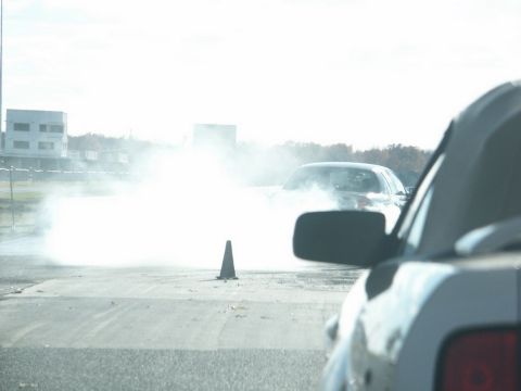 2001 Mercury Grand Marquis - A car performs a burnout, creating a large cloud of smoke on a track, as seen from the interior of another vehicle.
