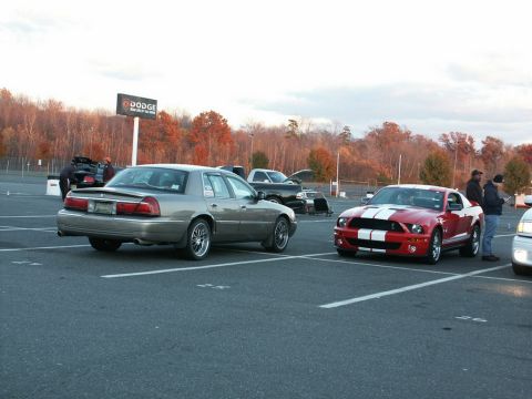 2001 Mercury Grand Marquis - A gray sedan is parked in a lot with a red sports car nearby.