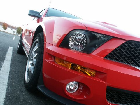 2001 Mercury Grand Marquis - Front view of a red Ford Mustang, showing the headlight, grille, and wheel. 2005 model year.