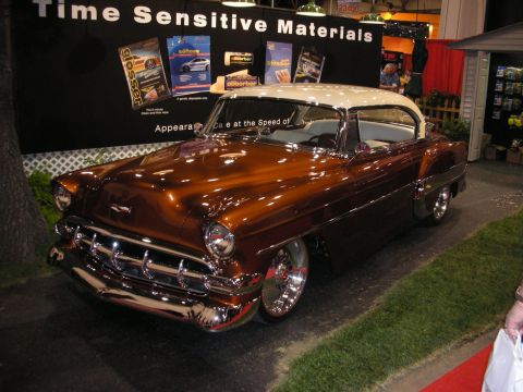 1998 Ford Crown Victoria - copper-brown custom early-1950s Chevrolet hardtop with a white roof, chrome bumper and grille displayed under a Time Sensitive Materials ba…
