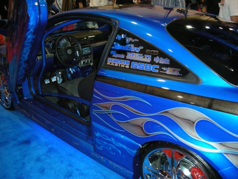 1998 Ford Crown Victoria - side of a blue custom coupe with an open door, flame graphics, chrome wheels and sponsor decals including SSBC on the glass.