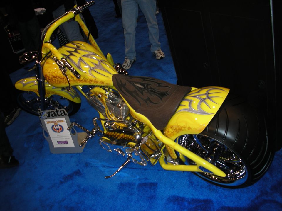 Yellow custom chopper motorcycle with tribal graphics on blue carpet