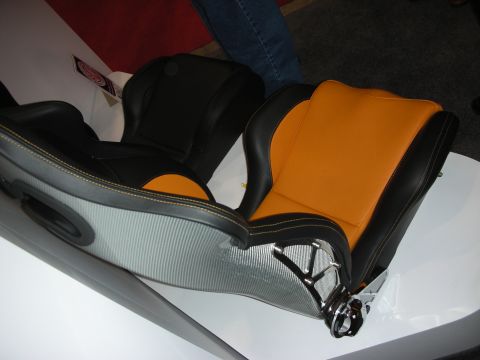 1998 Ford Crown Victoria - sport racing seat with a carbon-fiber shell, black-and-orange leather upholstery and a chrome mount, shown sideways.