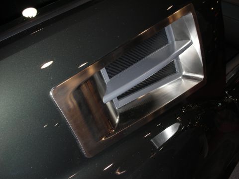 1998 Ford Crown Victoria - close-up of a recessed machined-aluminum and carbon-fiber air scoop set into a glossy dark body panel.
