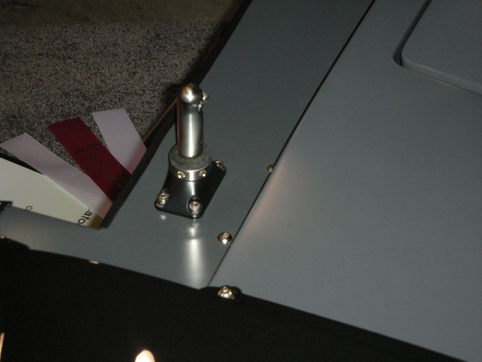 Gray painted panel with a metal ball-stud pivot and rivets, papers tucked behind it
