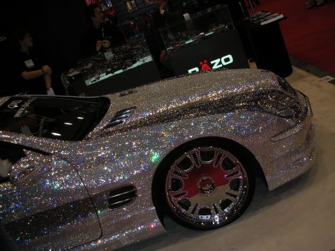 1998 Ford Crown Victoria - silver convertible entirely covered in sparkling crystals, riding on a chrome multi-spoke wheel with pink accents.