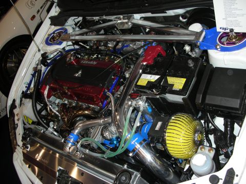 1998 Ford Crown Victoria - tightly packed engine bay shows a red valve cover, polished turbo piping, yellow filter and blue hoses in a white car.