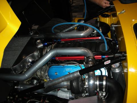 1998 Ford Crown Victoria - twin-turbo engine with red fuel rails, blue cover and large turbos is crammed into the engine bay of a yellow car.