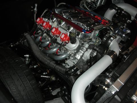 1998 Ford Crown Victoria - detailed V8 engine with red coil packs, polished intake and silver tubular headers sits in a custom engine bay.