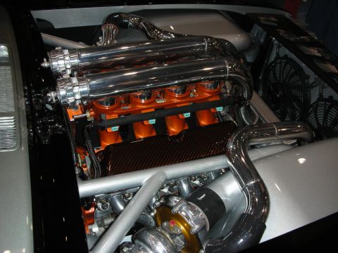 1998 Ford Crown Victoria - polished twin-turbo V8 with orange runners and a carbon-fiber panel is mounted in a silver bay next to electric cooling fans.