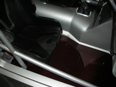 1998 Ford Crown Victoria - close-up of a custom car interior shows silver bodywork, a tubular roll bar and molded black panels in dim light.