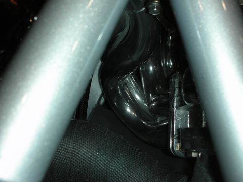 1998 Ford Crown Victoria - glossy black molded component sits in an engine bay, framed by a silver tubular roll-cage bar above it.