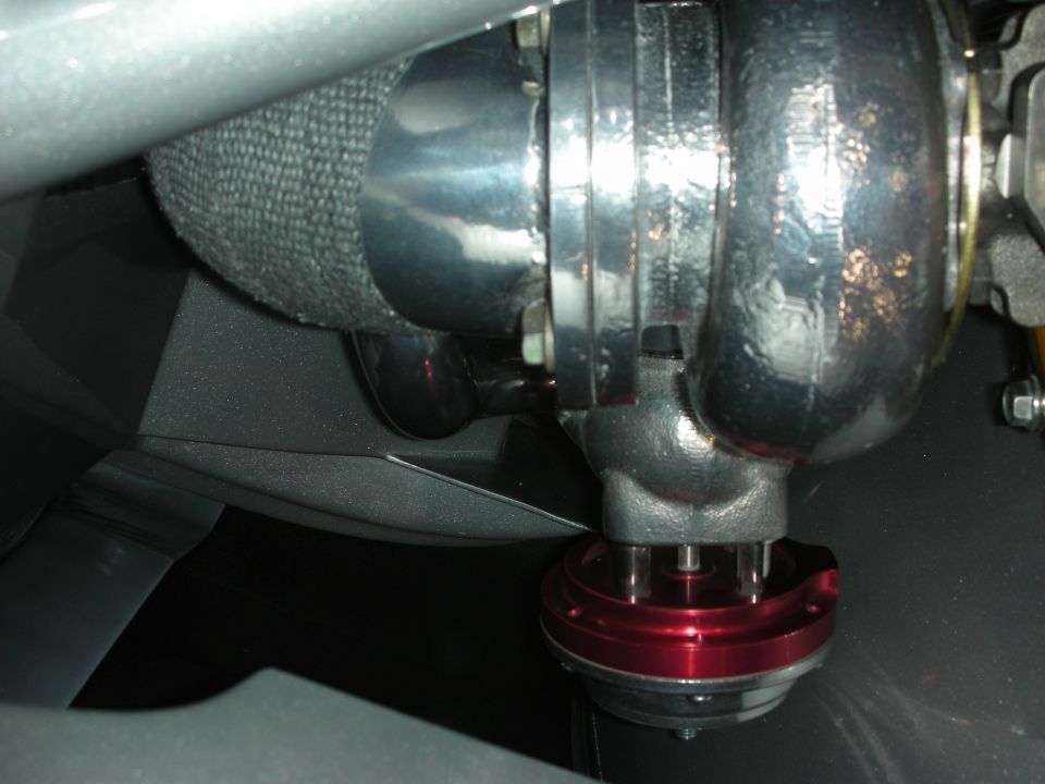 Turbocharger with polished compressor housing and red anodized wastegate in an engine bay