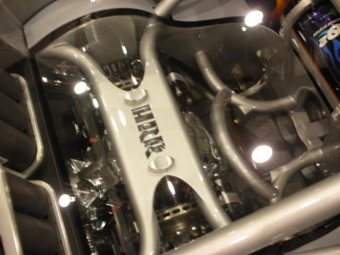 1998 Ford Crown Victoria - polished silver engine cover with raised lettering and curved tubular runners is lit from above at a show.