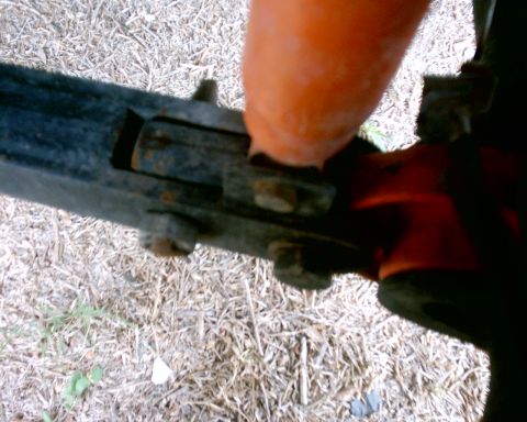 1979 Ford Bronco - Close-up of an orange component attached to a black metal frame with visible bolts.