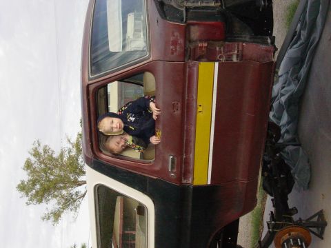 1979 Ford Bronco - Children peer out the window of a maroon and white SUV. The vehicle's rear section is exposed, suggesting it is being worked on.