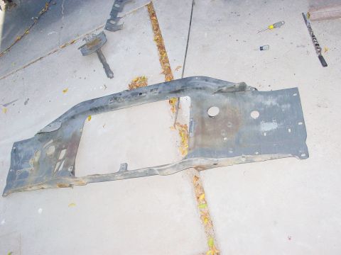 1979 Ford Bronco - A detached vehicle radiator support lies on a concrete surface, surrounded by fallen leaves and a few tools.