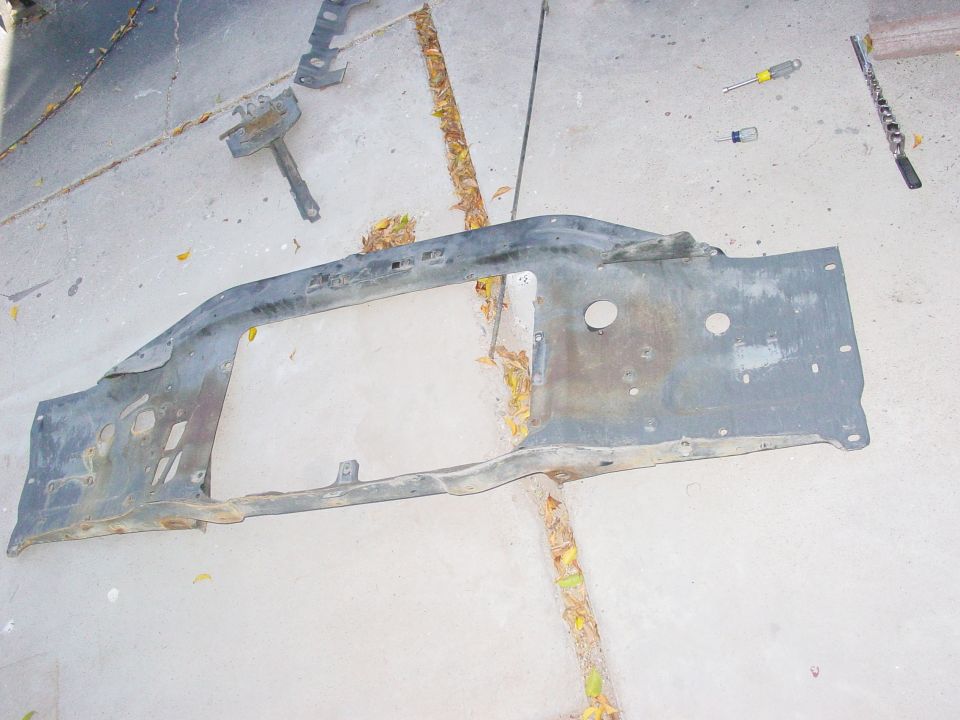 Gray metal radiator support on concrete with scattered leaves and tools