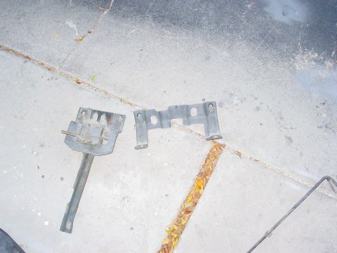 1979 Ford Bronco - Two metal brackets are shown lying on a concrete surface.