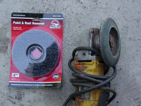 1979 Ford Bronco - A paint and rust remover disc and an angle grinder are laid out on a concrete surface.