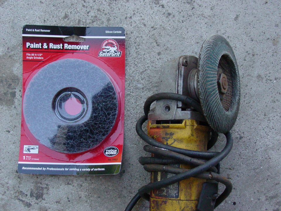 Paint and rust remover disc next to a yellow angle grinder with a green abrasive disc
