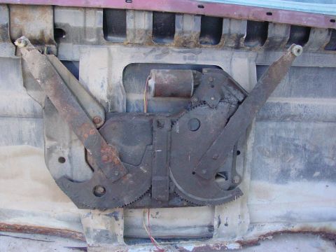 1979 Ford Bronco - Close-up of a corroded window regulator mechanism, showing gears and motor components.