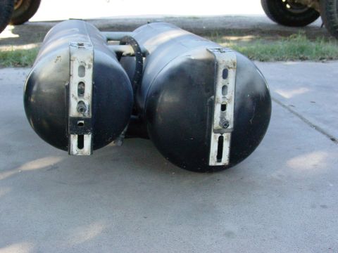 1979 Ford Bronco - Dual propane tanks are mounted beneath a vehicle, with visible brackets and straps.