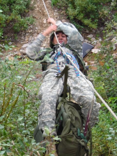 2003 Jeep TJ - A soldier practices rappelling down a steep, vegetated incline with a rope and backpack.
