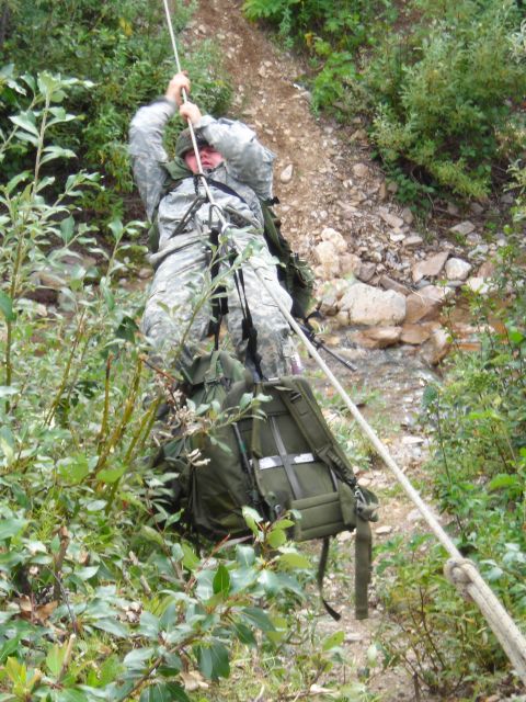 2003 Jeep TJ - A soldier is rappelling down a steep, rocky, and vegetated slope using a rope and harness.