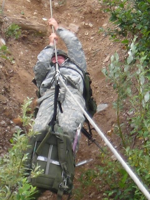 2003 Jeep TJ - A soldier in camouflage gear rappels down a steep, dirt slope, holding onto a rope for support.