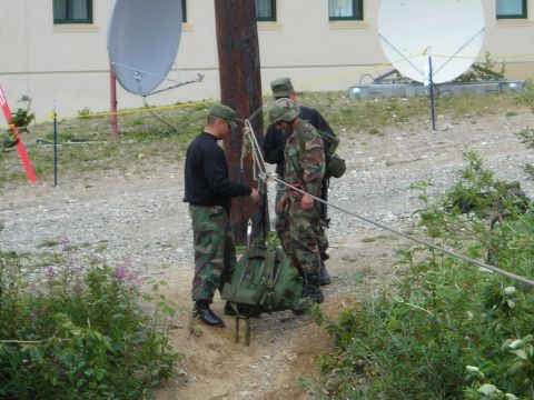 2003 Jeep TJ - Military personnel appear to be setting up or taking down equipment near a building with satellite dishes.