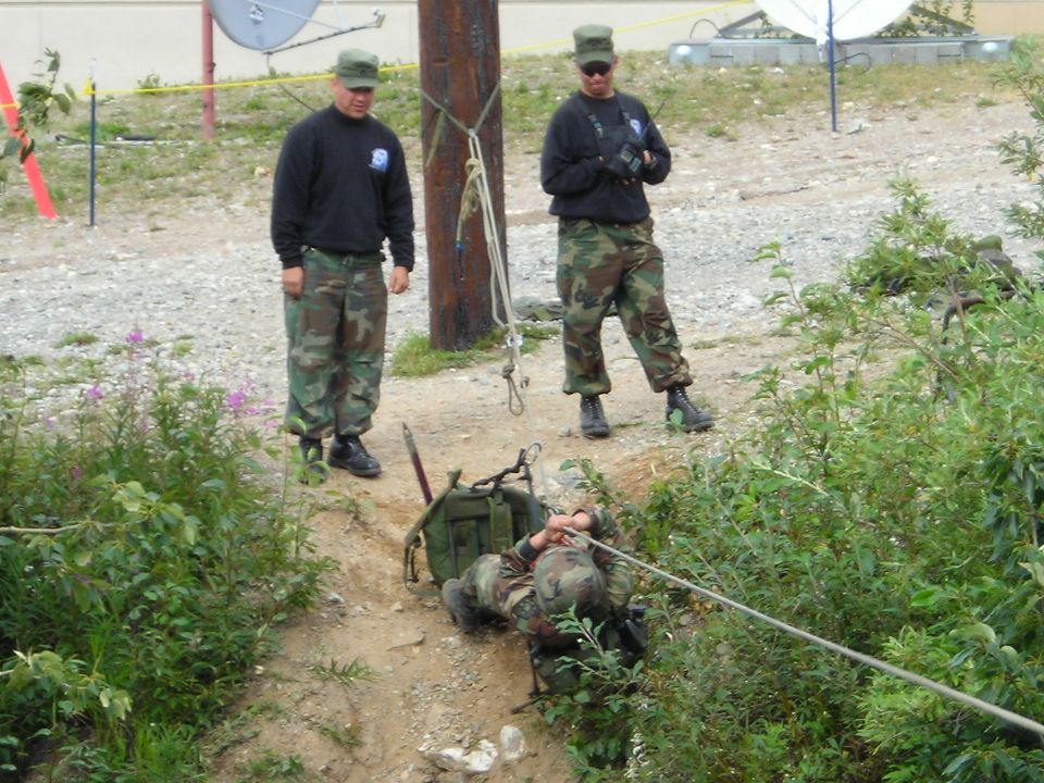 Military personnel conduct a rope rescue training exercise in a ditch