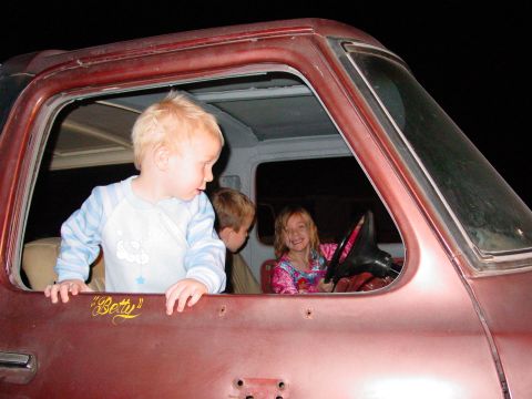 1979 Ford Bronco - Children peer out of the windows of a red Ford Bronco, with one child in the driver's seat.