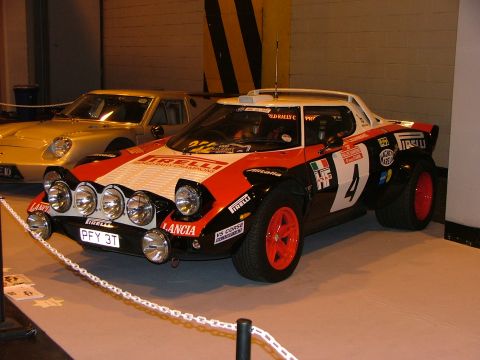 2001 Ford Fiesta - A Lancia Stratos rally car is displayed indoors, with another vehicle in the background.