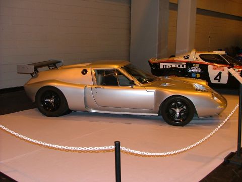 2001 Ford Fiesta - A silver sports car with a rear spoiler is displayed next to another race car.