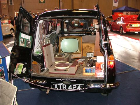 2001 Ford Fiesta - Vintage van interior filled with retro electronics, including a TV and record player. Another car is in the background.