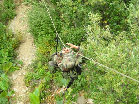 2003 Jeep TJ - A soldier navigates a steep, vegetated slope using a rope for descent.