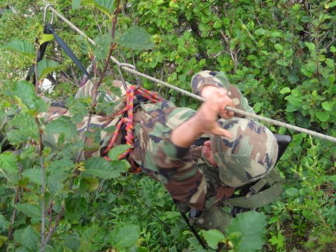 2003 Jeep TJ - Two soldiers in camouflage gear are seen rappelling down a wooded incline, utilizing ropes and harnesses for descent.