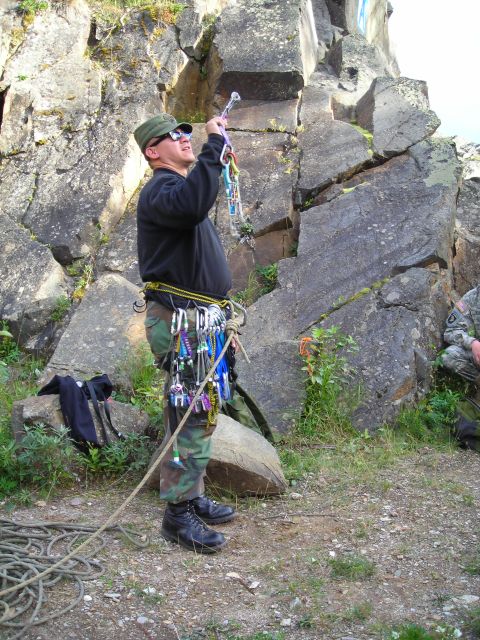 2003 Jeep TJ - A climber is geared up and ready to climb a rocky cliff face, with ropes and equipment laid out.