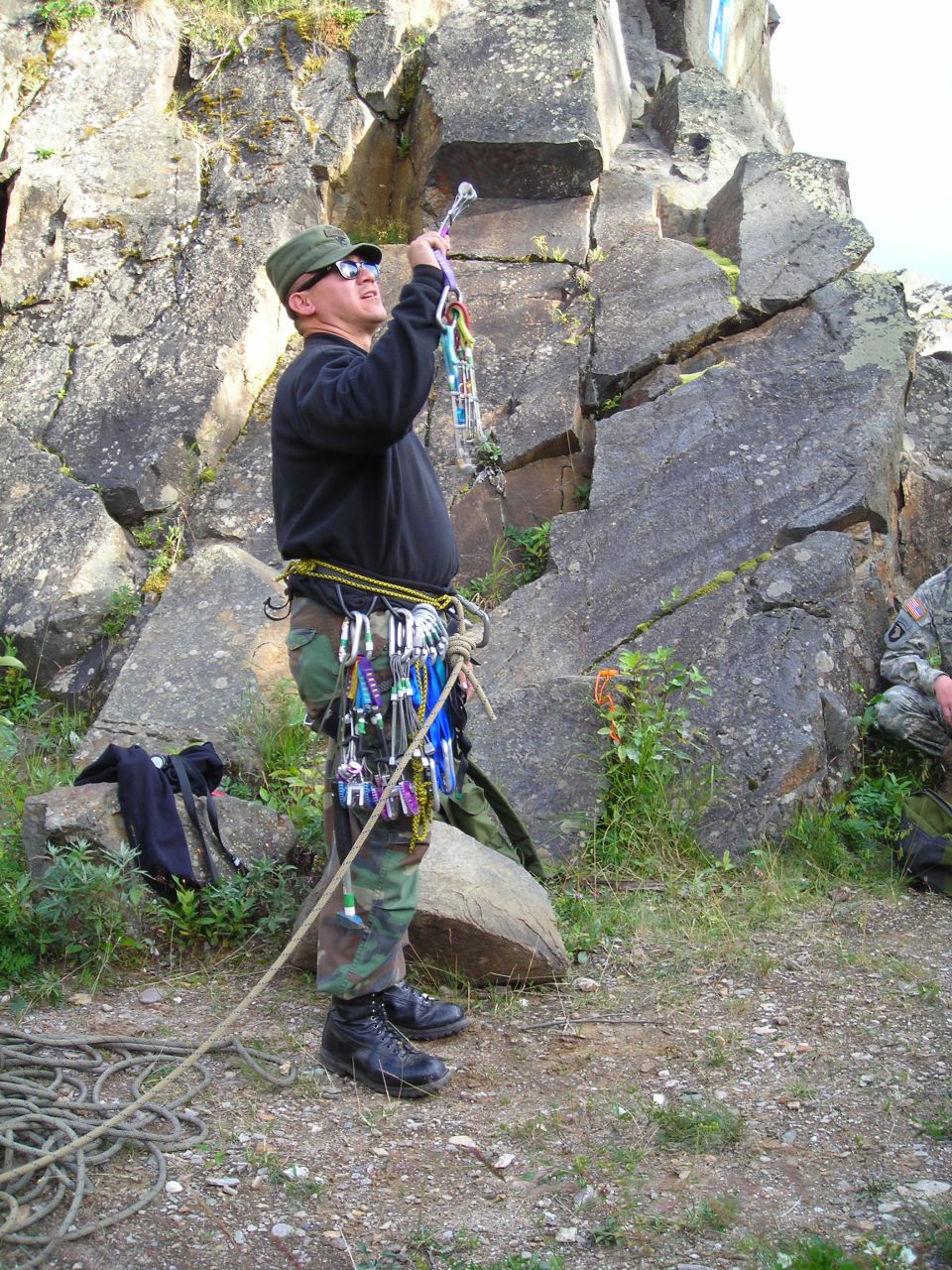 Rock climber with carabiners and rope preparing to ascend a cliff
