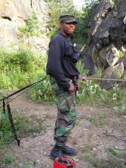 2003 Jeep TJ - A man prepares for climbing activities near a rocky outcrop with ropes and safety equipment visible.