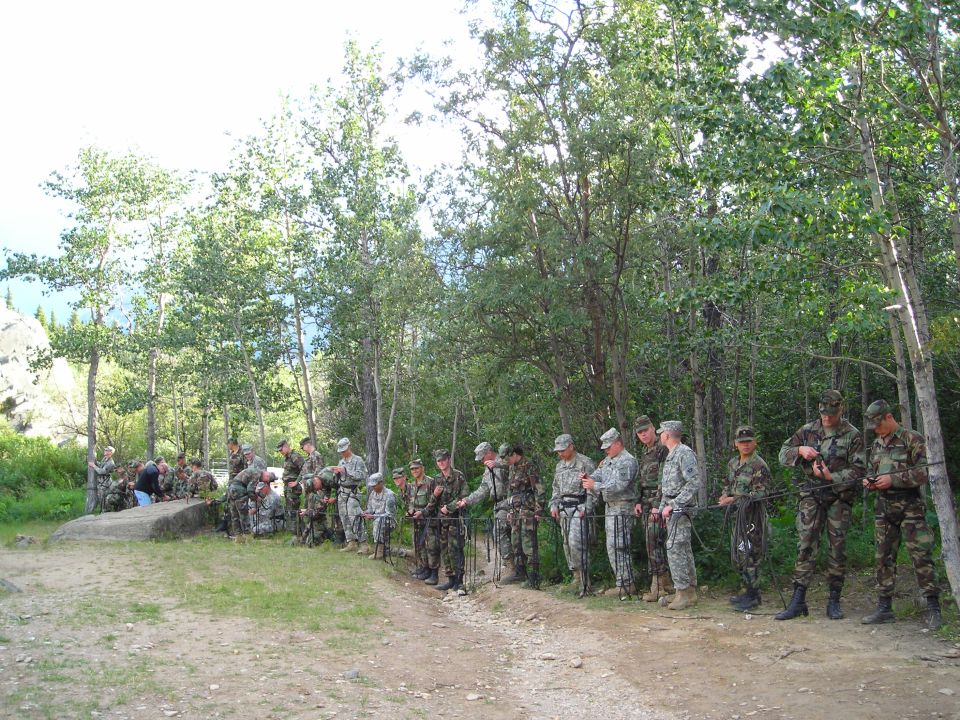Group of soldiers in uniform practicing rappelling with ropes in a wooded area
