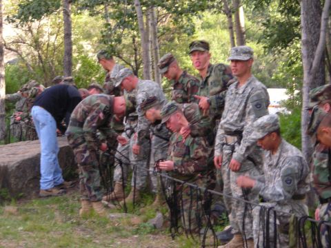 2003 Jeep TJ - A group of soldiers in camouflage uniforms are gathered outdoors, appearing to be engaged in some form of training or activity.